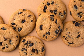 Many delicious chocolate chip cookies on beige background, flat lay