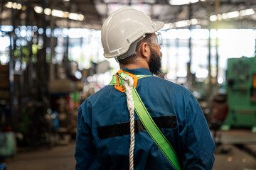 The technician is working in a steel factory. Back view shot of the Industrial engineer wearing protective clothing puts on hard hat.