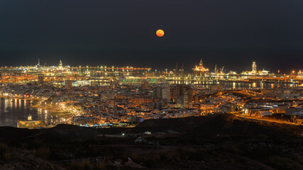 Night view of city and ocean, with orange full moon, Las Palmas de Gran Canaria, Spain
