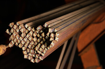 Thin metal rods bunch in cold plant warehouse macro view