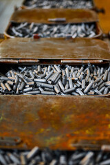 Metal containers full of bullet casings on table at plant