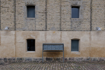 Outdoor exterior view, aluminium post box in front of old rough brick facade industrial building.