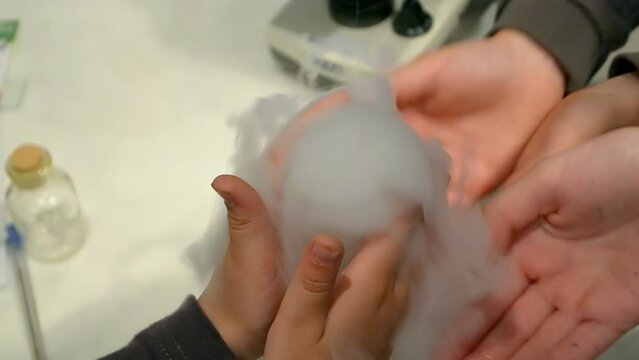 chemistry experiment closeup, kid hands over white fog diversity