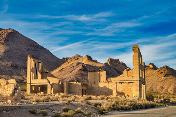 Ghost town stone ruins of an old building in a mountainous desert landscape on a clear day. - Powered by Adobe