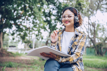 Fototapeta premium Asian woman sitting and writing in the garden