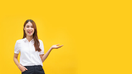 Women smiling and showing hand to presenting product with empty space on isolated yellow background