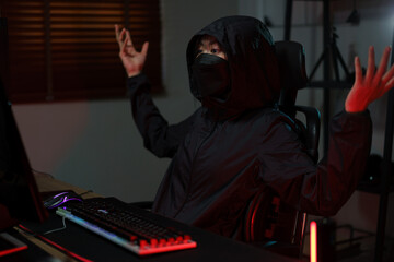 Hacker in hoodie raising hands while having problem with hacking programming system or server