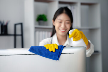 Person cleaning room, cleaning worker is using cloth to wipe computer screen in company office room. Cleaning staff. Concept of cleanliness in the organization.