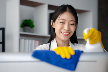 Person cleaning room, cleaning worker is using cloth to wipe computer screen in company office room. Cleaning staff. Concept of cleanliness in the organization.