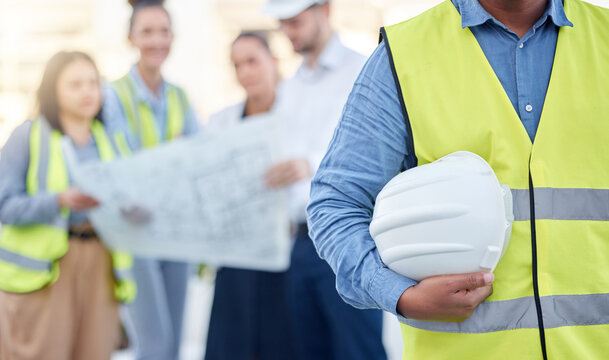 Helmet, Construction And An Architect Standing On A Building Site With His Team Planning In The Background. Leadership, Architecture And Renovation With An Engineer Holding A Hard Hat For Maintenance