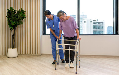 Fototapeta na wymiar Woman physical therapist in blue uniform help an elderly to exercise and practice walking on walker or cane. Healthcare and medicine concept.