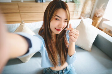 Pretty young asian female with big smile sitting at living room. She having fun taking light...