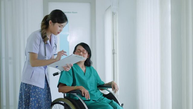 asian young Doctor caring for her elderly patient at senior daycare,cheerful nurse wheeling Senior patient concept.Asian elderly patient in wheelchair at hospital looking out window with new hope