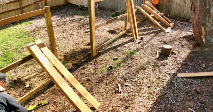 Building a Fence Flying Aerial Drone Shot Two Builders Attach Picket Boards to Backer Rails and Posts Sunny Day Outside