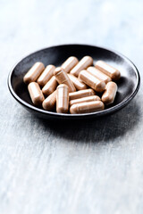 Guarana capsules. Bright wooden background. Close up. Copy space.	