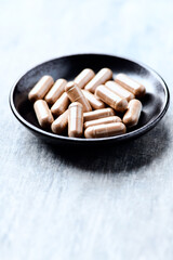 Guarana capsules. Bright wooden background. Close up. Copy space.	