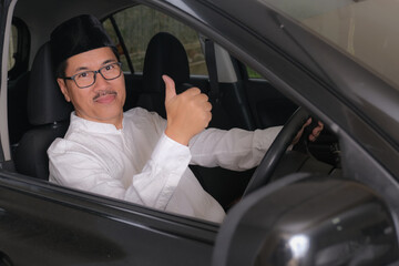 A middle-aged man about to drive gives an   ok sign with his thumb; happy expression.
