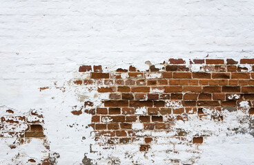 The texture of an old brick wall, painted white and partially crumbled