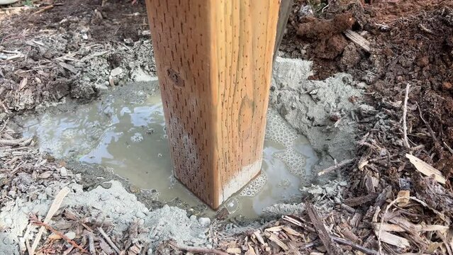 Setting a Level Fence Post Pouring Water on Concrete Built With Treated Cedar Wood