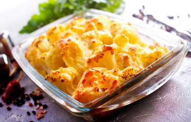Savory food: baked cauliflower with cheese, eggs and cream close-up in a baking dish on a table.