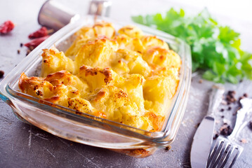 Savory food: baked cauliflower with cheese, eggs and cream close-up in a baking dish on a table.