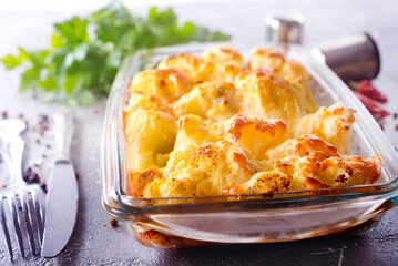 Savory food: baked cauliflower with cheese, eggs and cream close-up in a baking dish on a table.