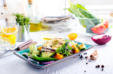 Green vegan salad with cucumber and avocado on a concrete table. View from above.