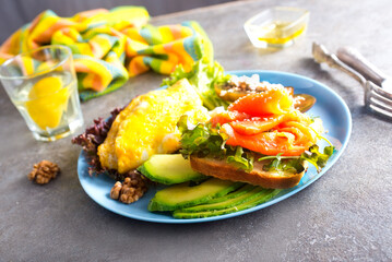 Omelette or omelet, fresh arugula and tomato salad and toasts with butter and salted salmon. Breakfast.