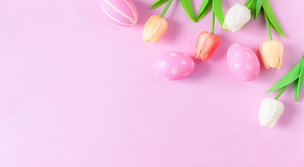 Naklejka na ściany i meble Happy Easter holiday greeting card concept. Colorful Easter Eggs and spring flowers on pastel pink background. Flat lay, top view, copy space.