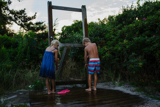 Rear view of siblings washing legs from tap water at Tobay Beach