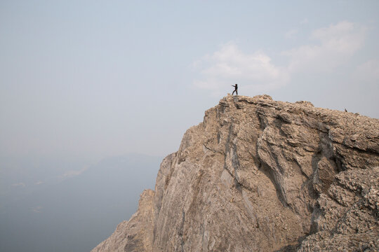 Low angle view of hiker standing on cliff against sky during foggy weather