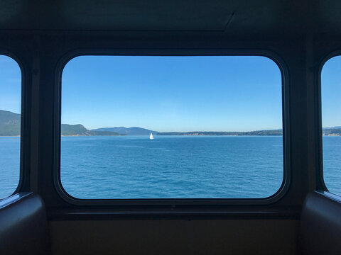 Sailboat sailing on river against clear sky seen through ferry window