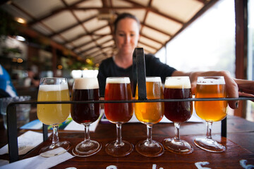 Woman picking craft beer from rack on table at restaurant
