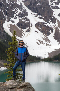 Hiker with hands in pockets standing on rock against Moraine Lake and mountain
