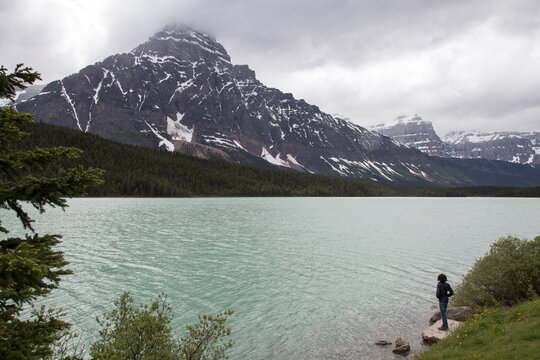 High angle view of hiker standing on rock by Waterfowl Lake against mountains