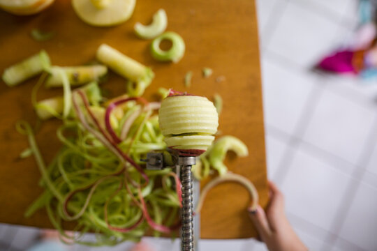 Overhead view of apple being peeled off using peeler on table at home