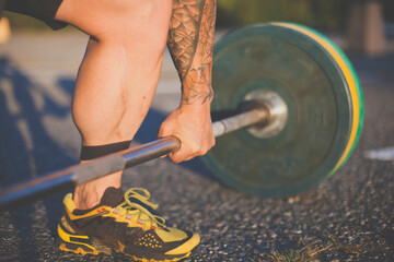 Low section of man lifting barbell at park