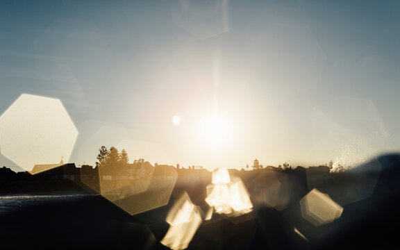 Silhouette houses by sea against sky during sunset