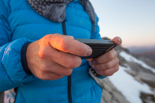 Midsection of hiker using smart phone against mountains during winter