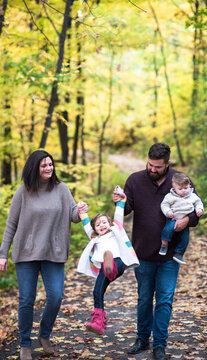 Man carrying son while swinging daughter with woman at park
