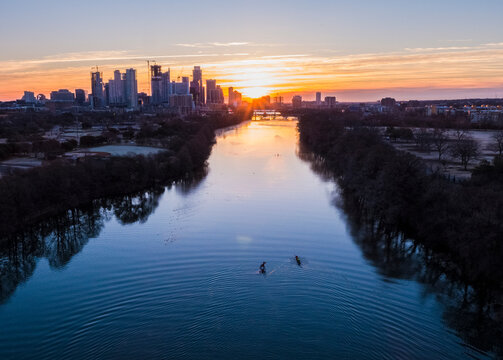 High angle distant view of people sculling on Lady Bird Lake against cityscape during sunrise