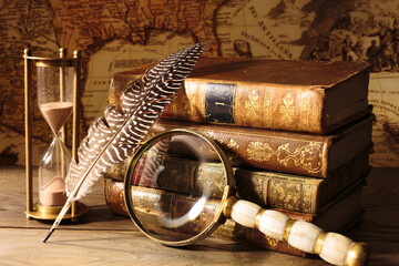 Antique still life. Medieval table with old map, magnifying glass, books, quill pen, sandwatch.