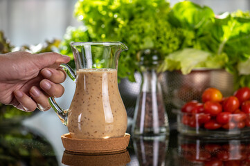 homemade sauces of salad dressings and olive oil in small glass jug including Japanese sesame seed. Glass jug of Japanese sesame seed salad dressings and olive oil.