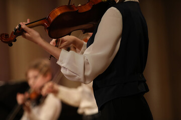 A musician playing the violin in the school orchestra at a concert