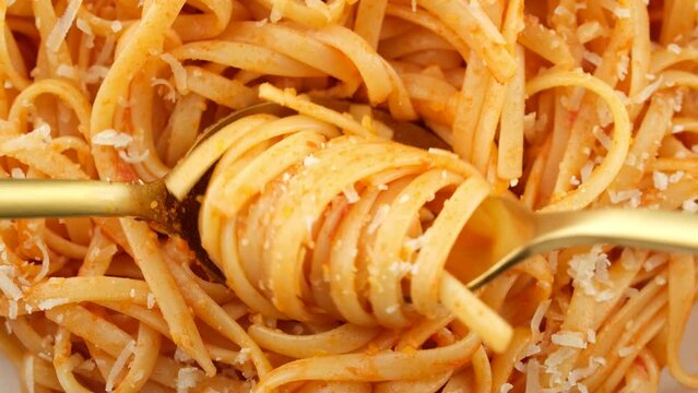 Eating spaghetti and parmesan cheese with fork and spoon