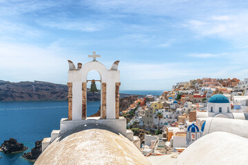 White bell tower in the background of the city of Oia. Santorini, Greece.