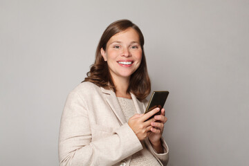 Fototapeta premium Pregnancy, technology and people concept. Beautiful happy pregnant woman using smartphone, portrait