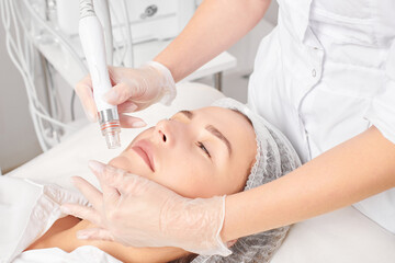 Cosmetologist makes aqua exfoliation for rejuvenation woman face skincare, anti aging cosmetic...