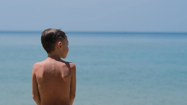 boy standing and looking at the sea