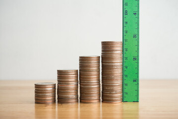 Green measuring ruler measure growth stack coins on wooden table white wall background copy space....